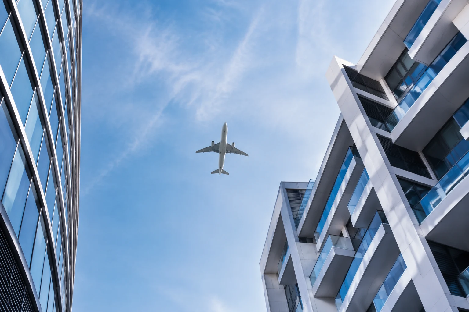 A passenger plane passing between modern buildings